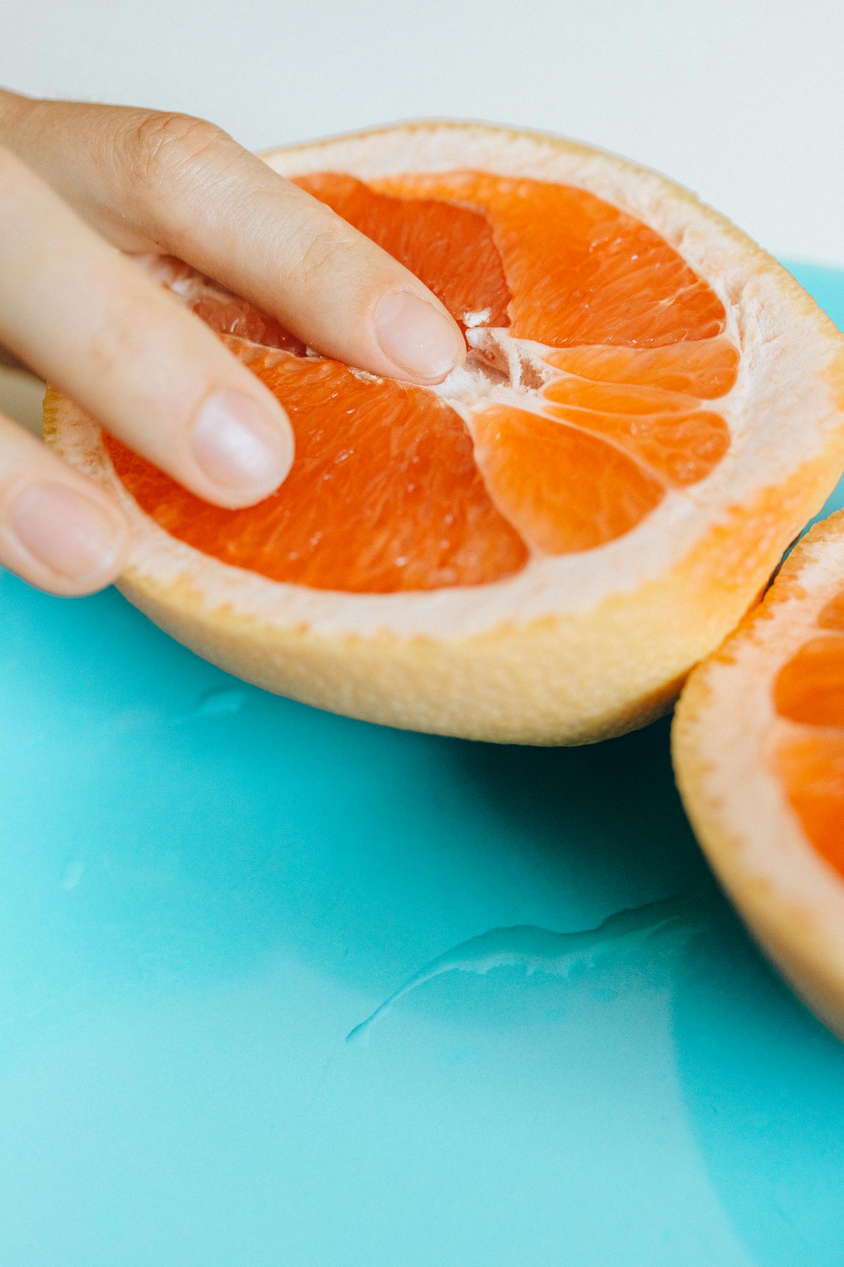 Artistic shot of a hand touching grapefruit, symbolizing sensuality.